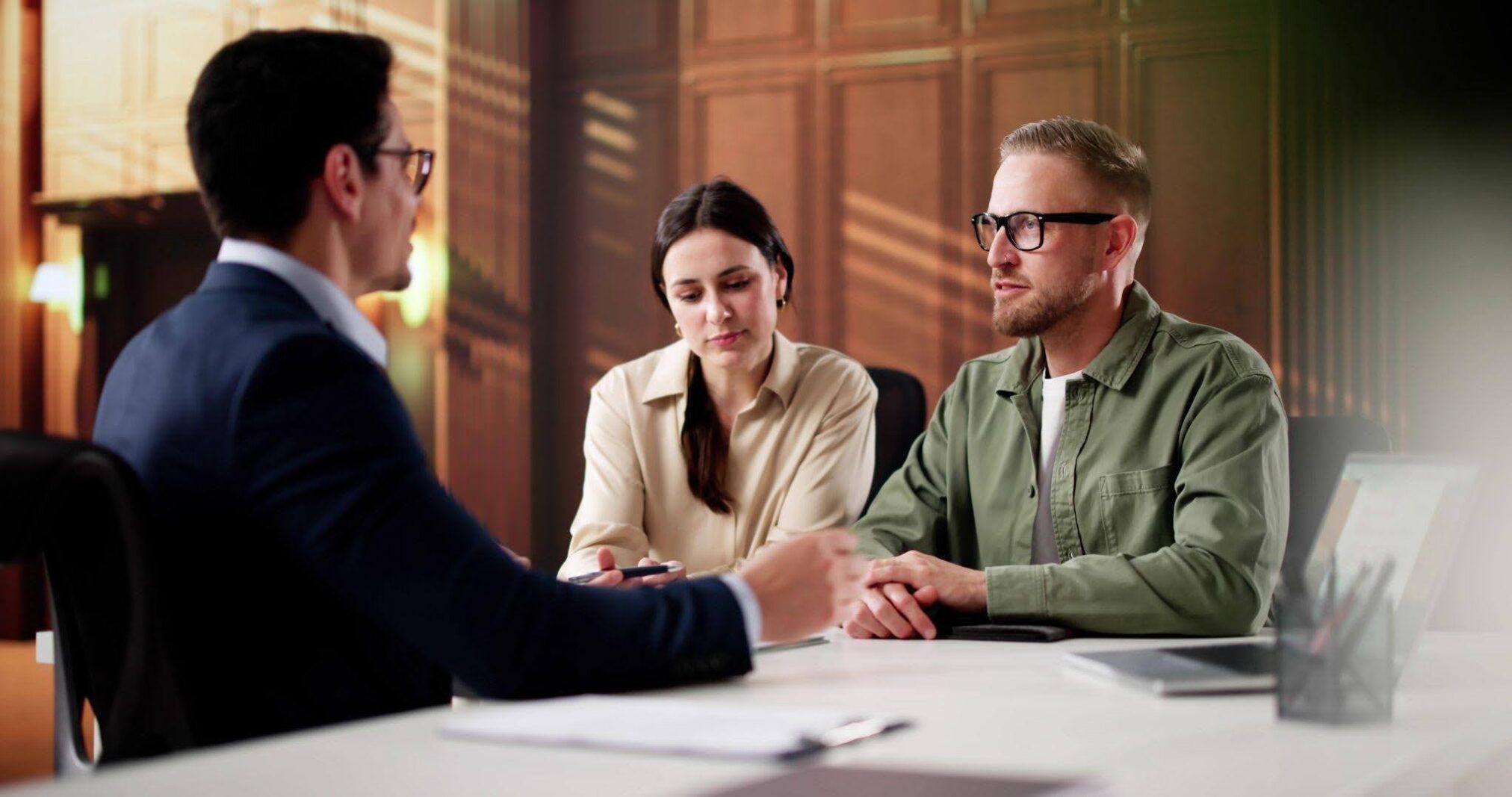 A man and woman seated at a table in an office engaged in discussion with documents in front of them