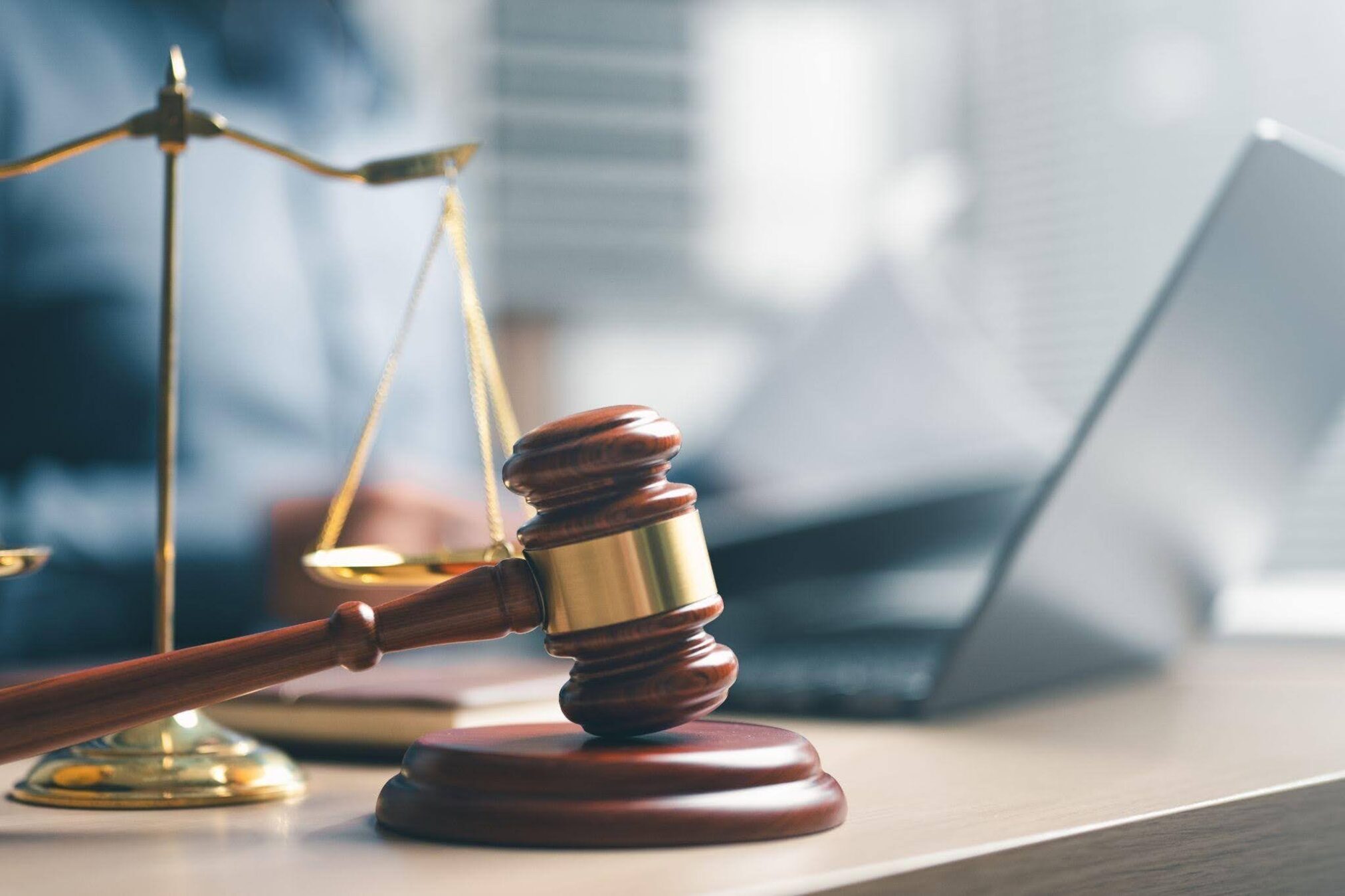 Close-up of a gavel and scales of justice on a wooden desk illustrating the theme of law and justice