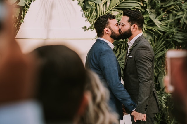 men-wearing-suit-kissing-in-front-of-people-3491999