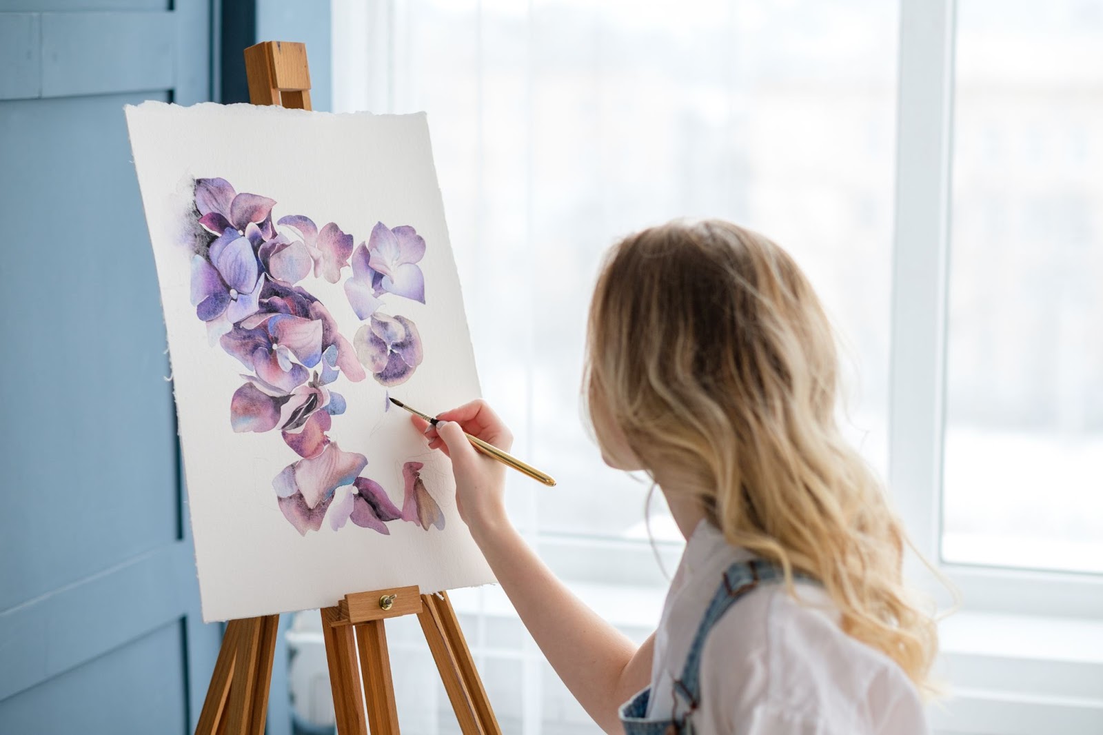 A woman painting purple flowers on a canvas, reflecting topics like co-parenting, divorce, and parenting
