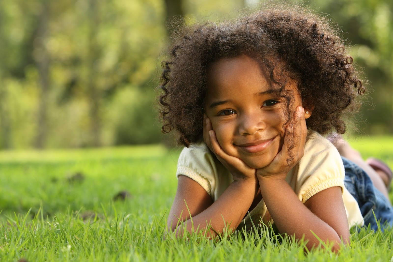 A young girl laying on the grass in a park, representing co-parenting, divorce, and parenting guideline