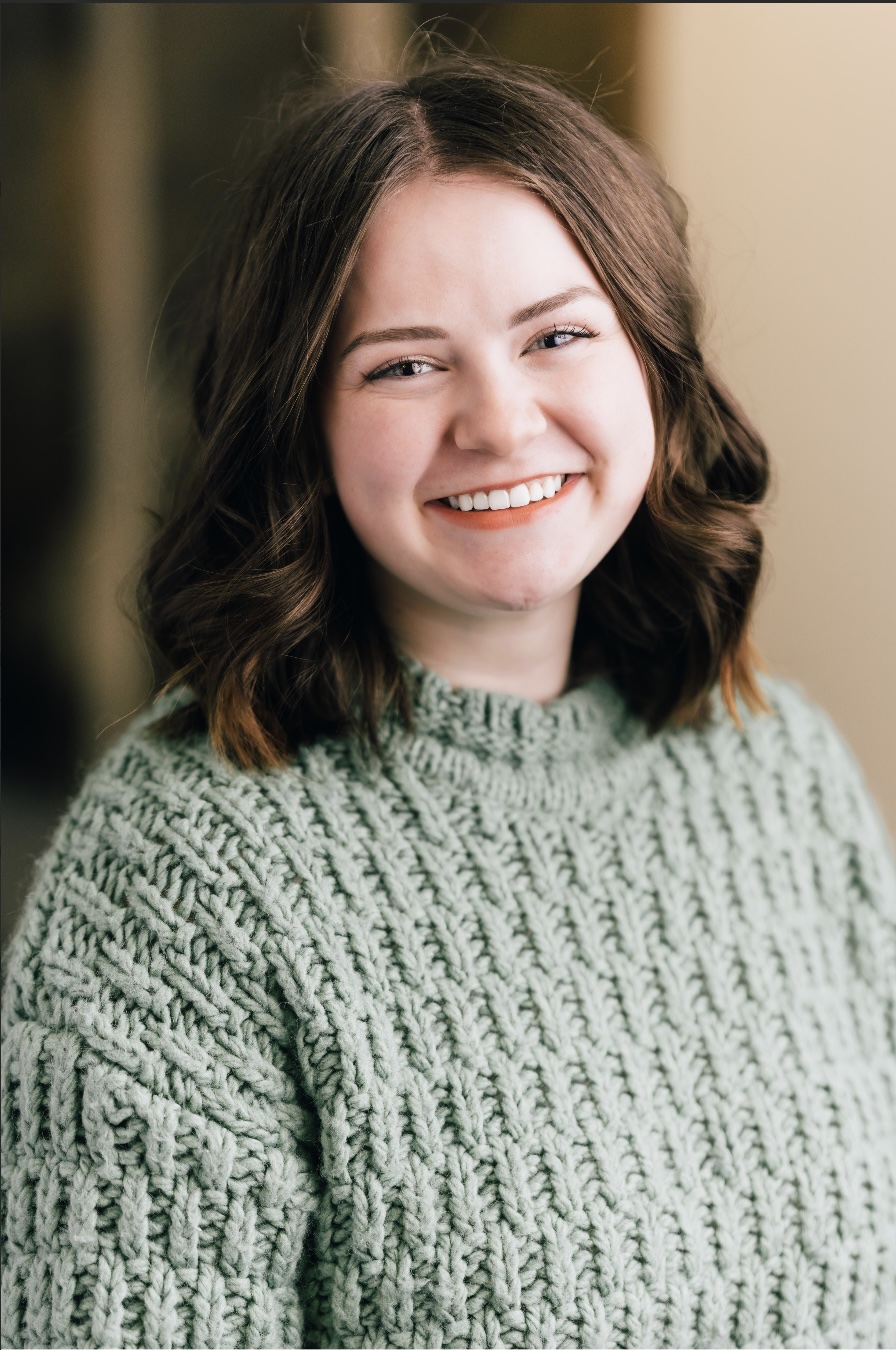 Portrait of LIVI DAVENPORT, wearing a green sweater and smiling