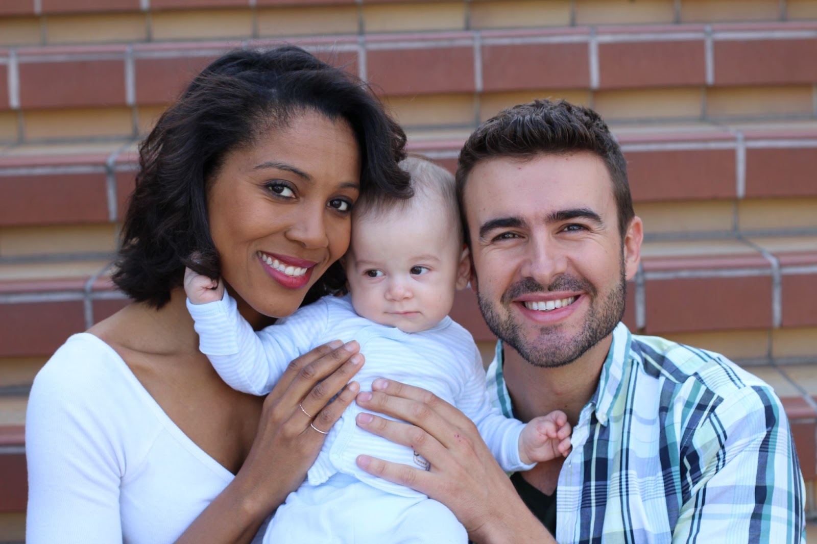 A smiling couple holds their baby, symbolizing love and unity in step-parent adoption and family growth.