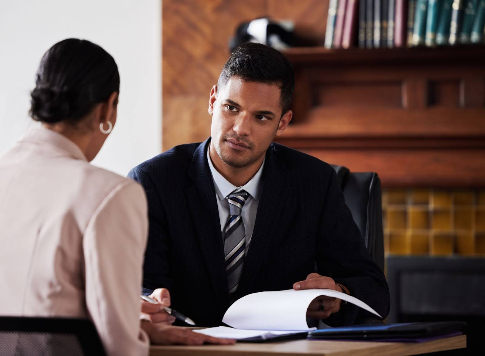 A man and woman in business attire seated at a desk, discussing professionally