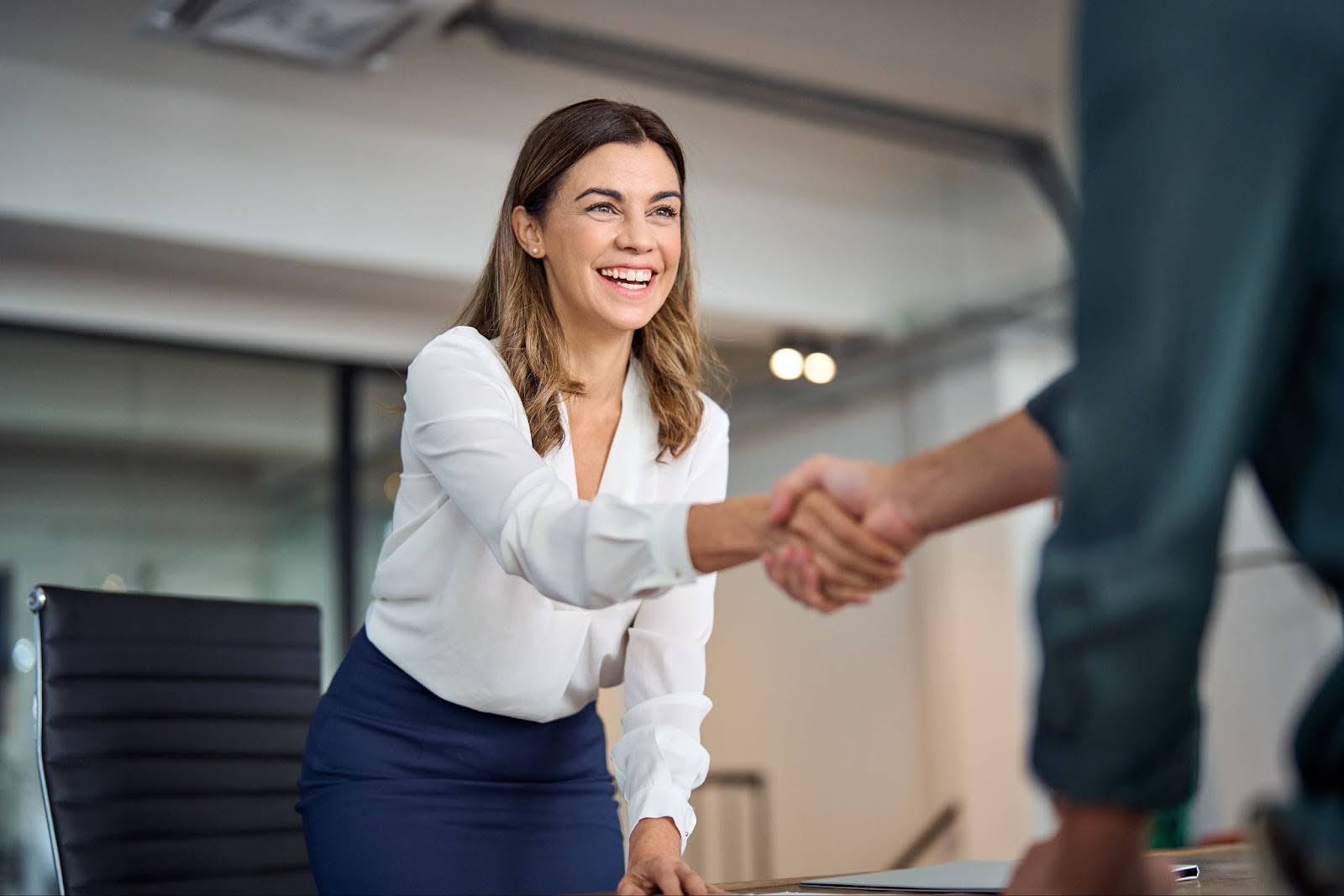 A woman and a man shaking hands in an office, symbolizing collaboration