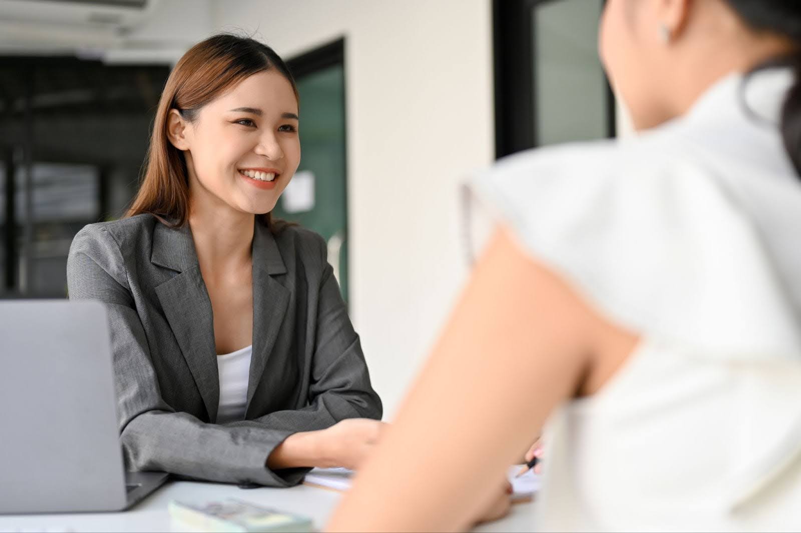 A woman in a business suit engages in conversation with another woman in a professional setting