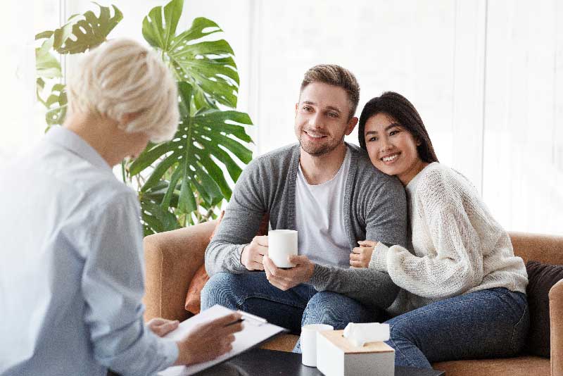 A couple enjoys coffee together while sitting comfortably on a couch, sharing a moment of relaxation and connection.