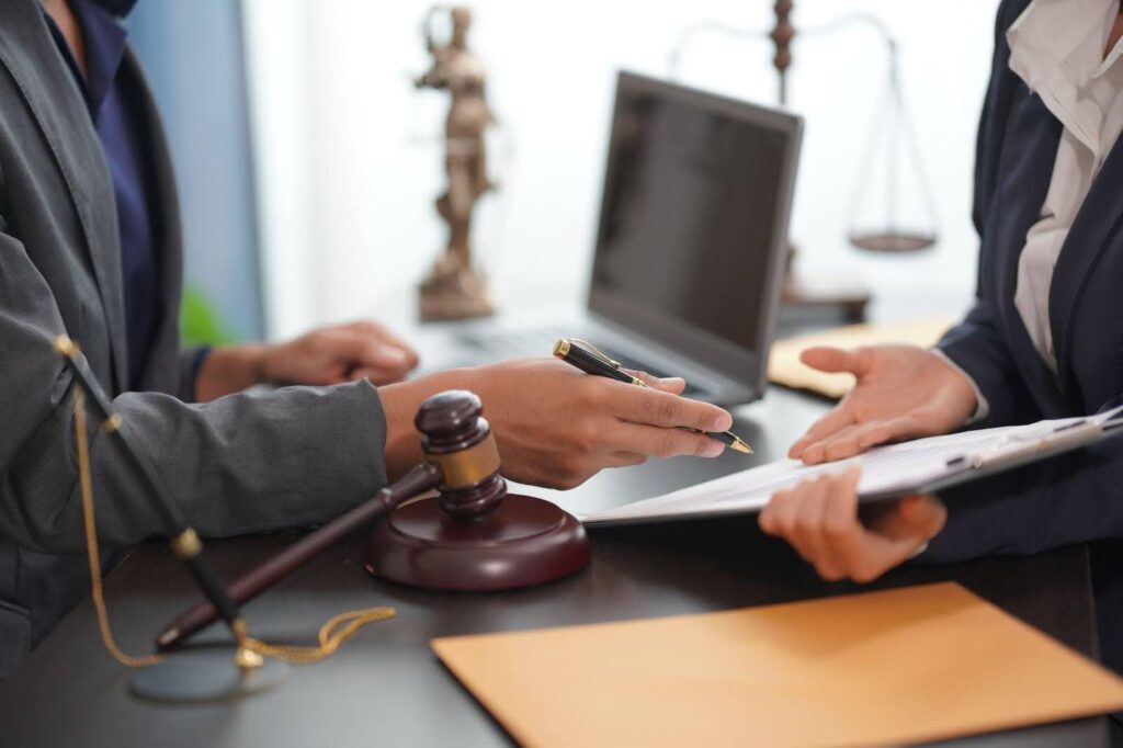 A lawyer and client discussing documents at a desk in a professional office setting