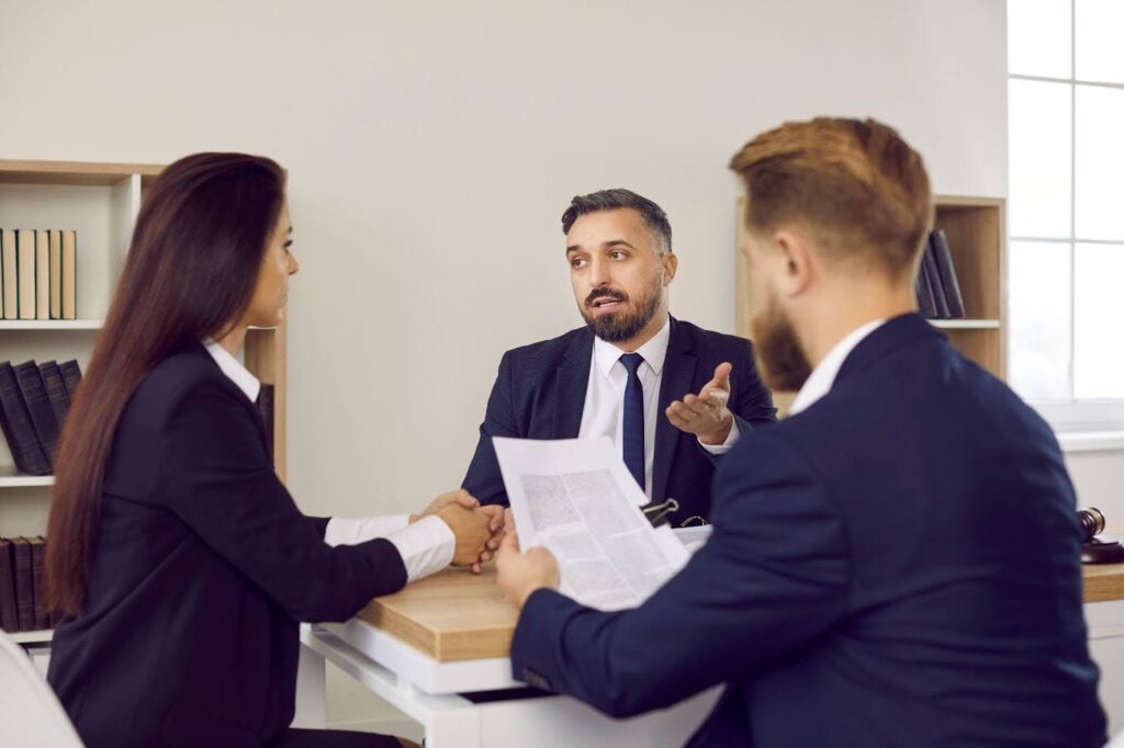 A man and woman in business attire engage in discussion with a third man