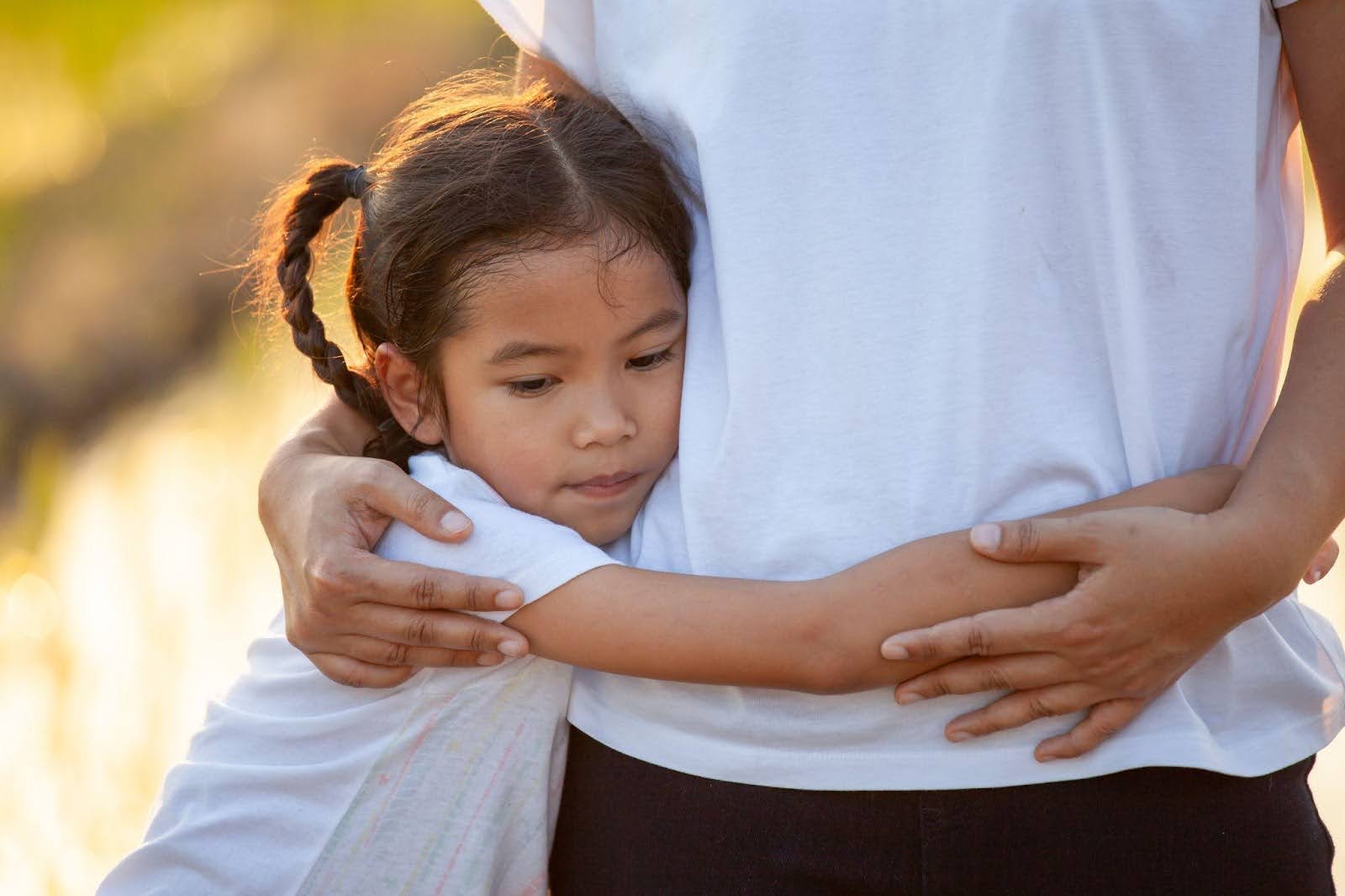 A young girl embraces her mother both smiling warmly in a moment of affection and connection