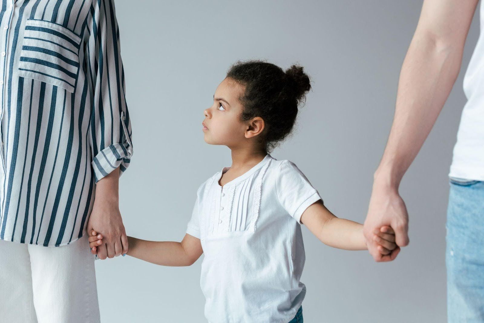 A young girl joyfully holds hands with her parents symbolizing family unity and love