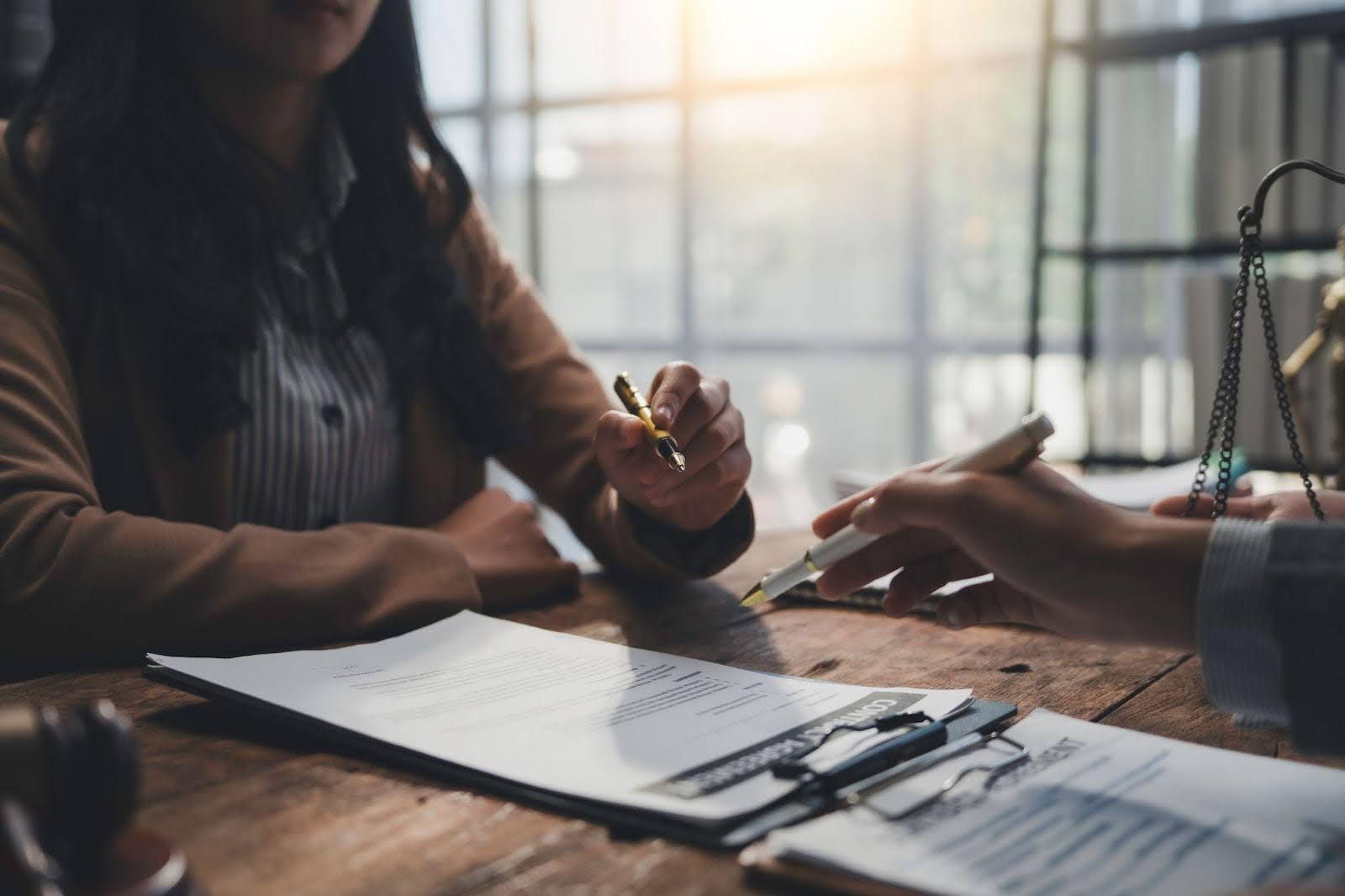 A lawyer is signing documents while seated next to a client both engaged in a legal consultation