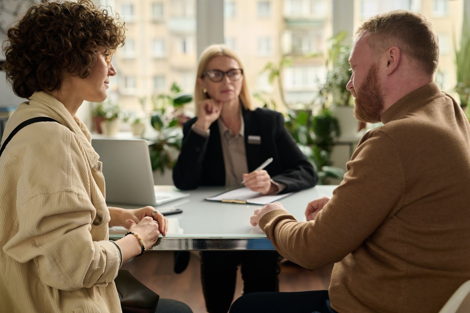 A man and woman engage in conversation with another couple in a modern office setting.