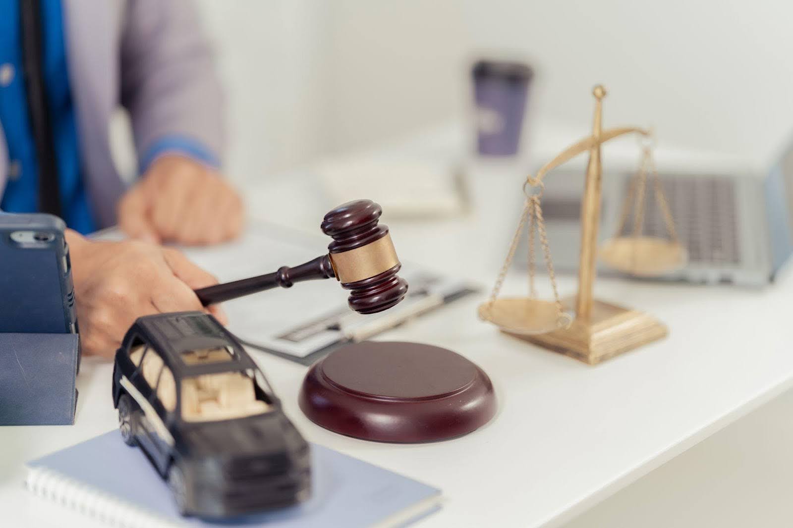 Lawyer hand holding a gavel and scales of justice on a polished desk symbolizing law and legal proceedings