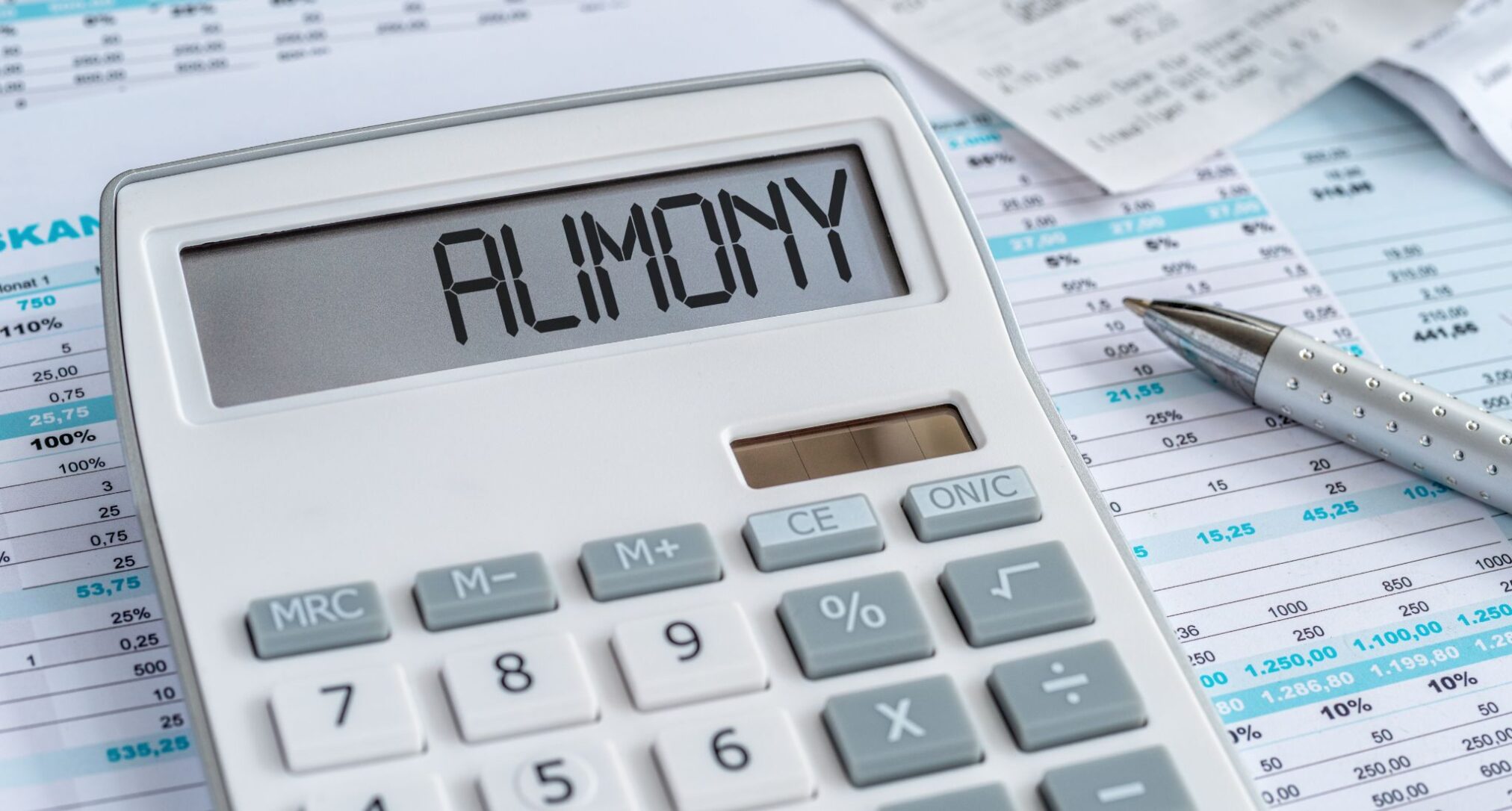 A white calculator with ALIMONY written on the screen, resting on financial documents.